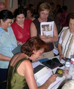 La profesora Concepción Lomba firmando ejemplares del libro recién presentado a sus paisanos.